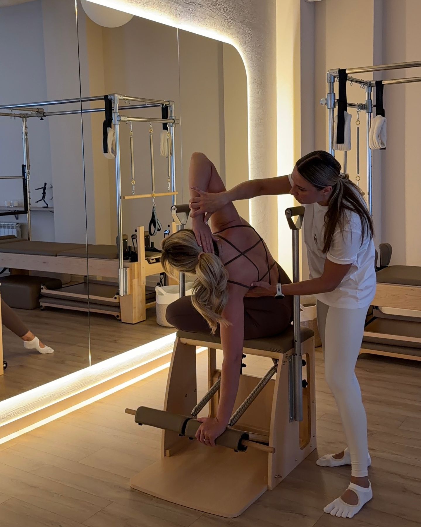 Тренер помогает клиентке на реформере в студии ProPilates
